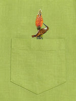 Load image into Gallery viewer, Woodpecker perched on a botanical branch above the pocket of the Vanchar hand-painted linen shirt.