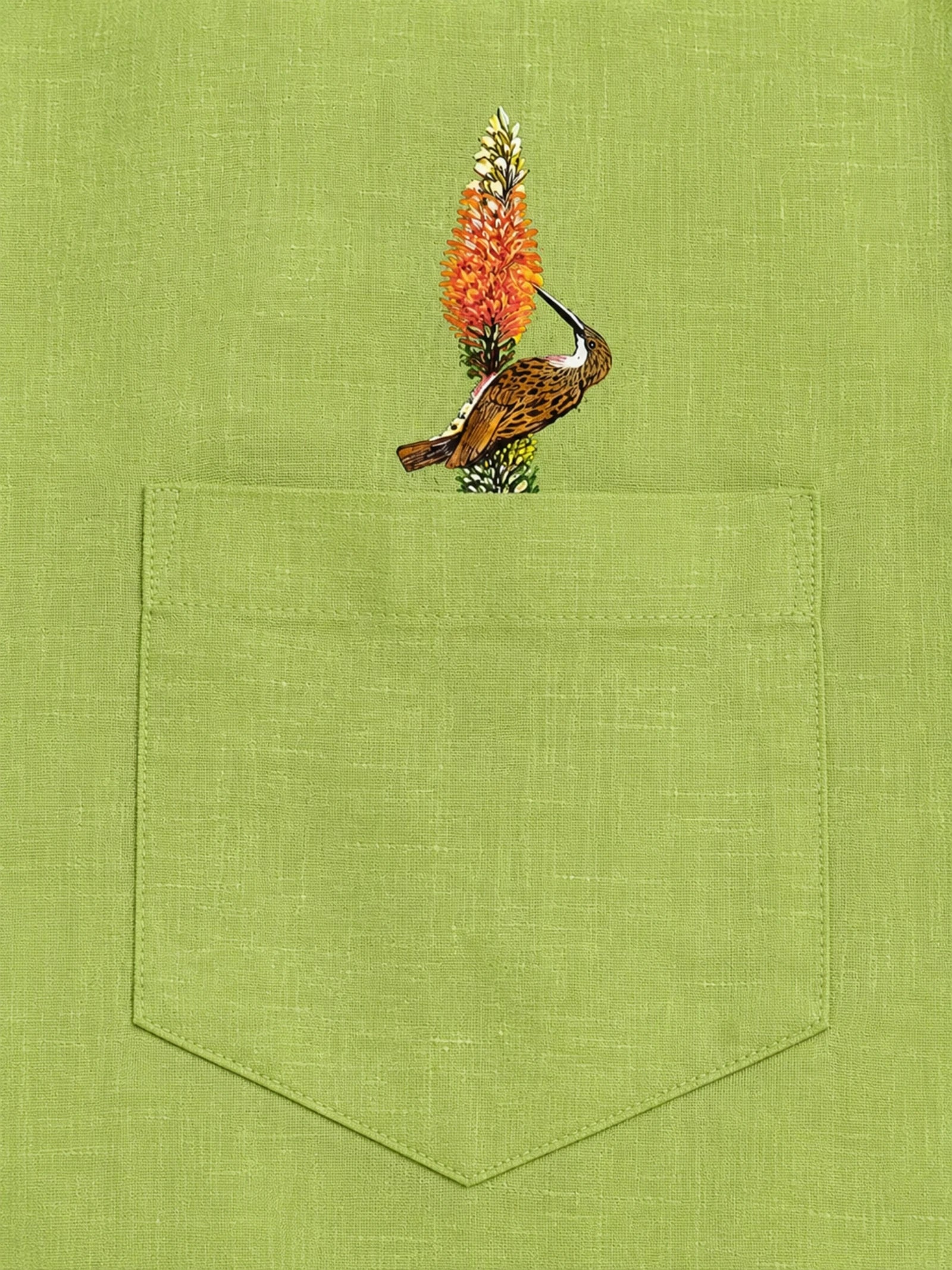 Woodpecker perched on a botanical branch above the pocket of the Vanchar hand-painted linen shirt.